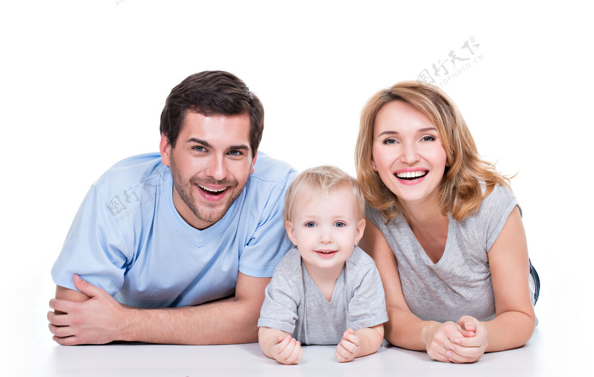 拥抱微笑的年轻父母和躺在地板上的孩子的照片-孤立孩子三撒谎