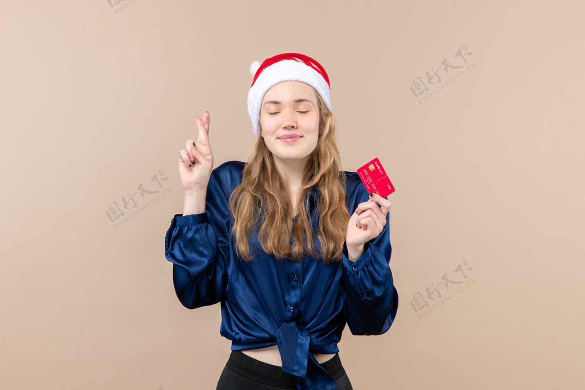 人正面图年轻女性手持红色银行卡上的粉色背景节日圣诞钱合影新年感慨情感年轻钱