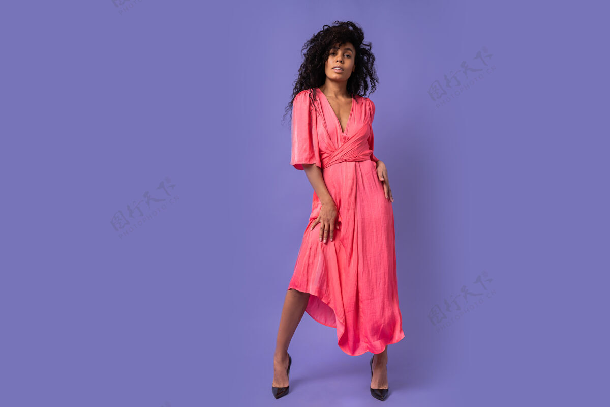 头发时尚自信的女人 卷发在紫色的墙上摆姿势穿着优雅的派对礼服春装全长积极表情紫罗兰