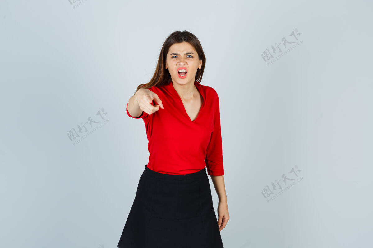 情绪穿红衬衫 黑裙子的年轻女子用食指指着镜头尖叫愤怒漂亮