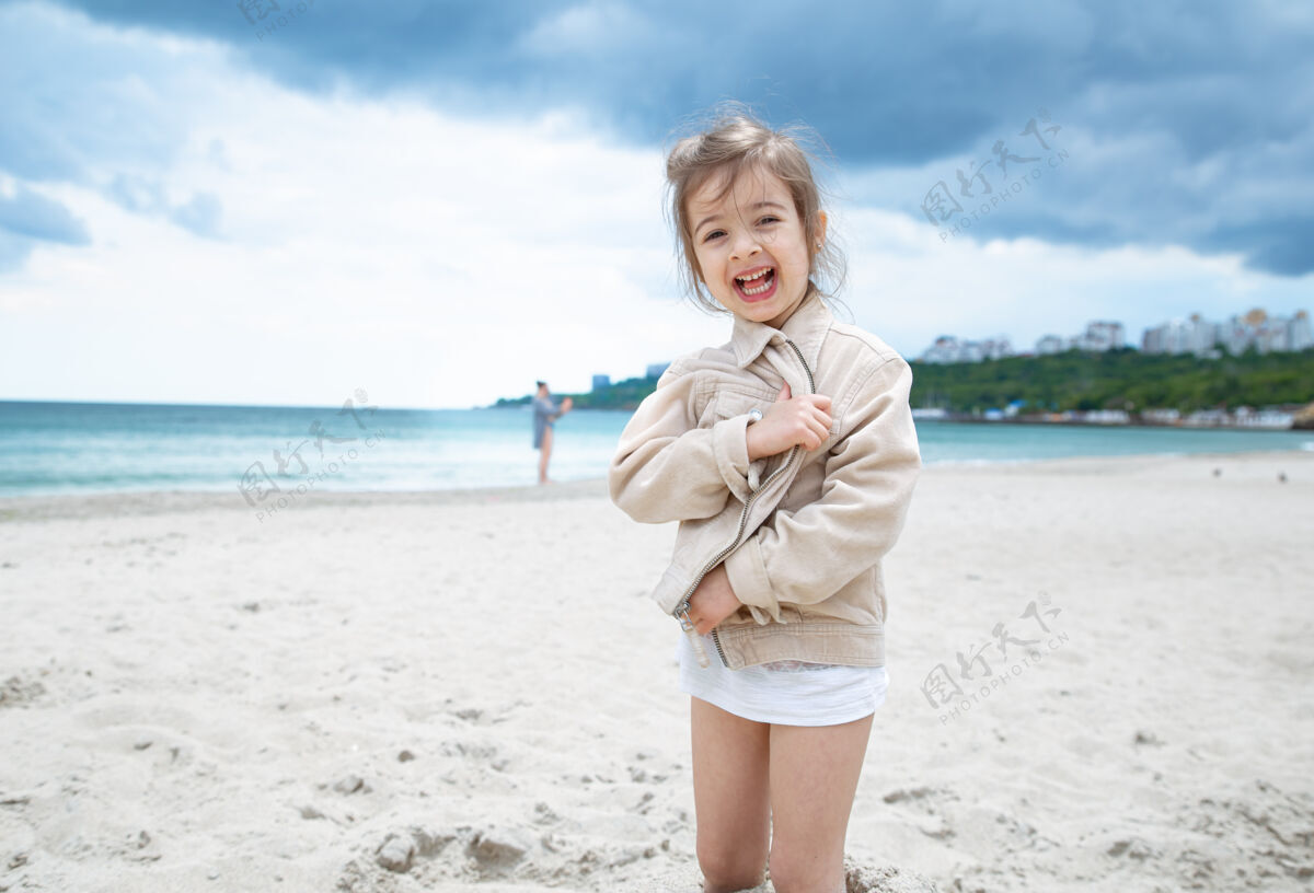 夏天快乐的小女孩在阳光明媚的日子在海边的海滩上风景模糊休息