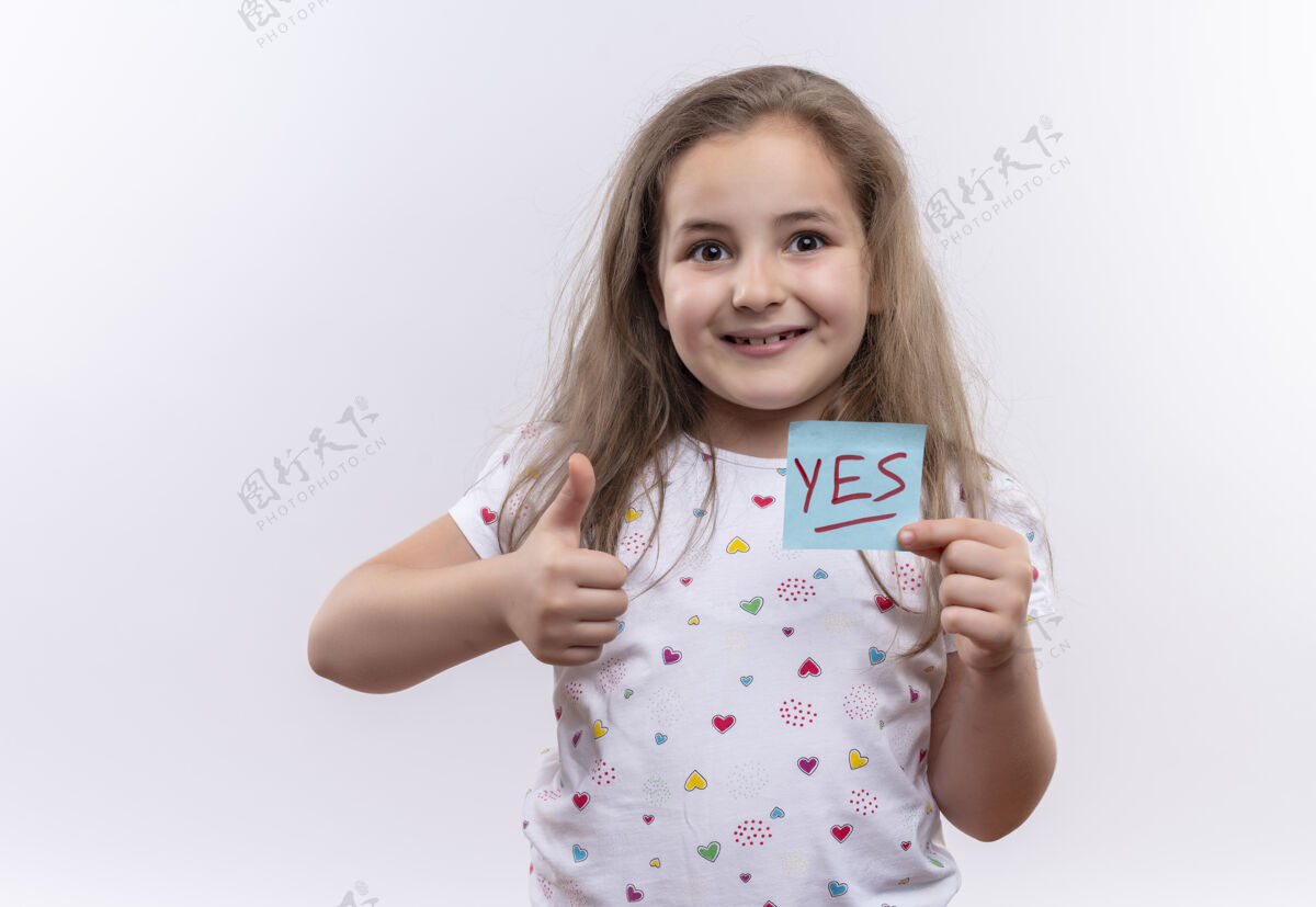拇指微笑的小女生穿着白色t恤拿着纸在孤立的白色背景上竖起大拇指向上学校小