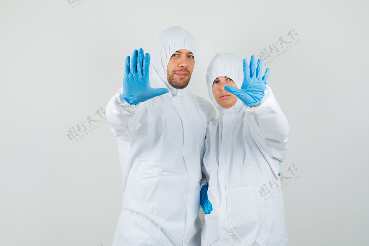 外观两个穿着防护服的医生在做停车手势讨论外套专业