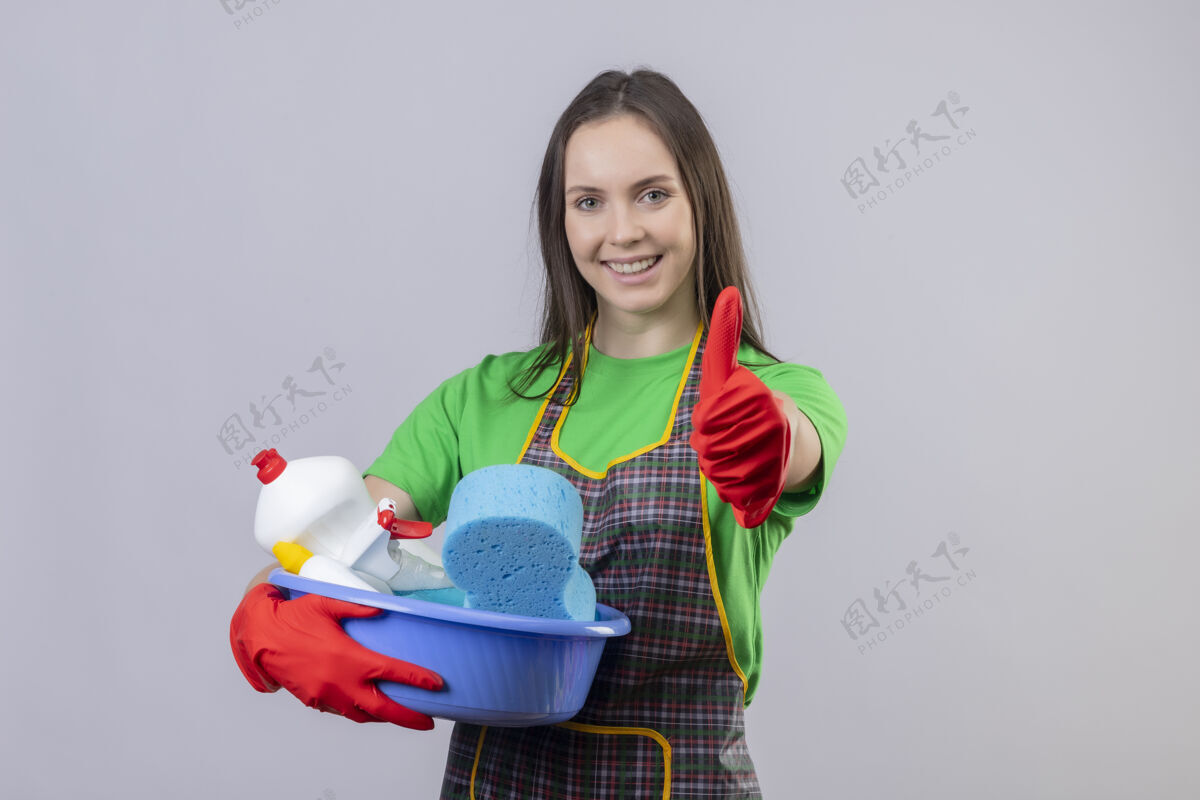 拇指一个穿着制服 戴着红手套 拿着清洁工具的年轻女孩高兴地清洁着 她的大拇指竖立在孤立的白色背景上工具手套年轻