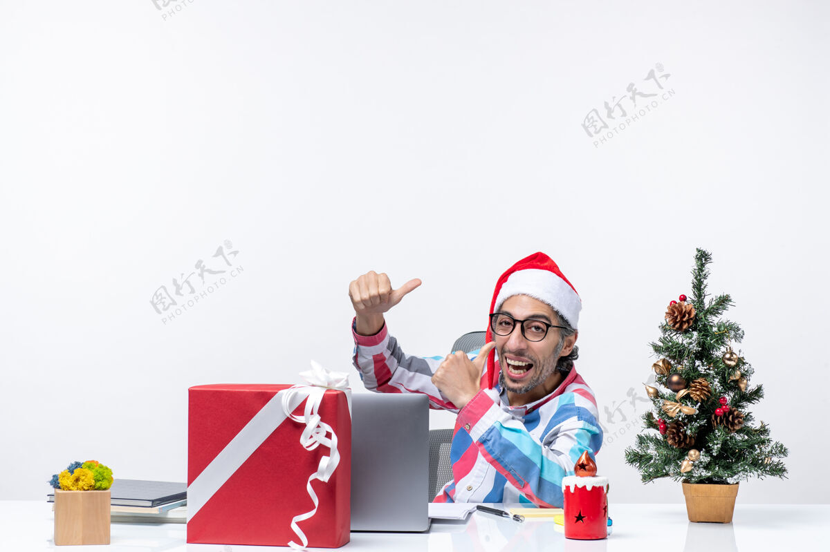 礼物正面图：坐在白色办公桌上工作的年轻男工人礼物坐风景
