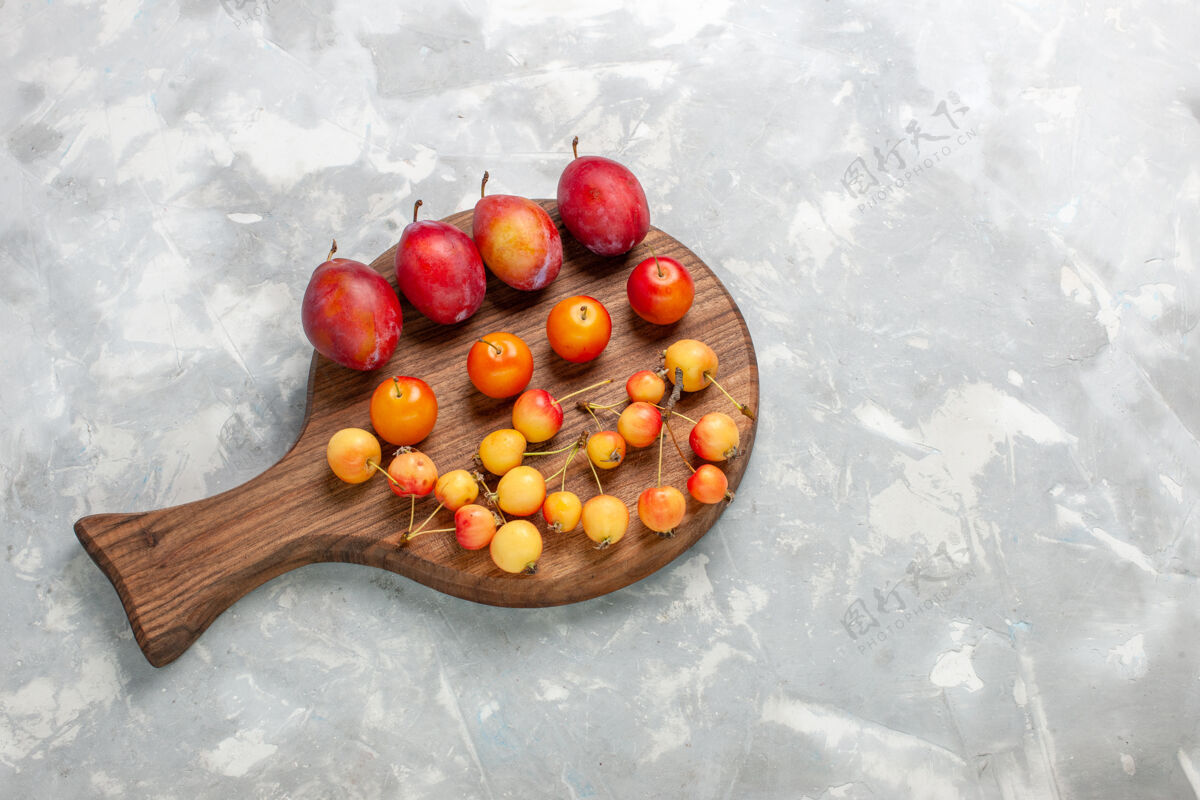 李子顶视图不同形状的李子酸和新鲜水果与樱桃放在浅白的桌子上水果健康樱桃