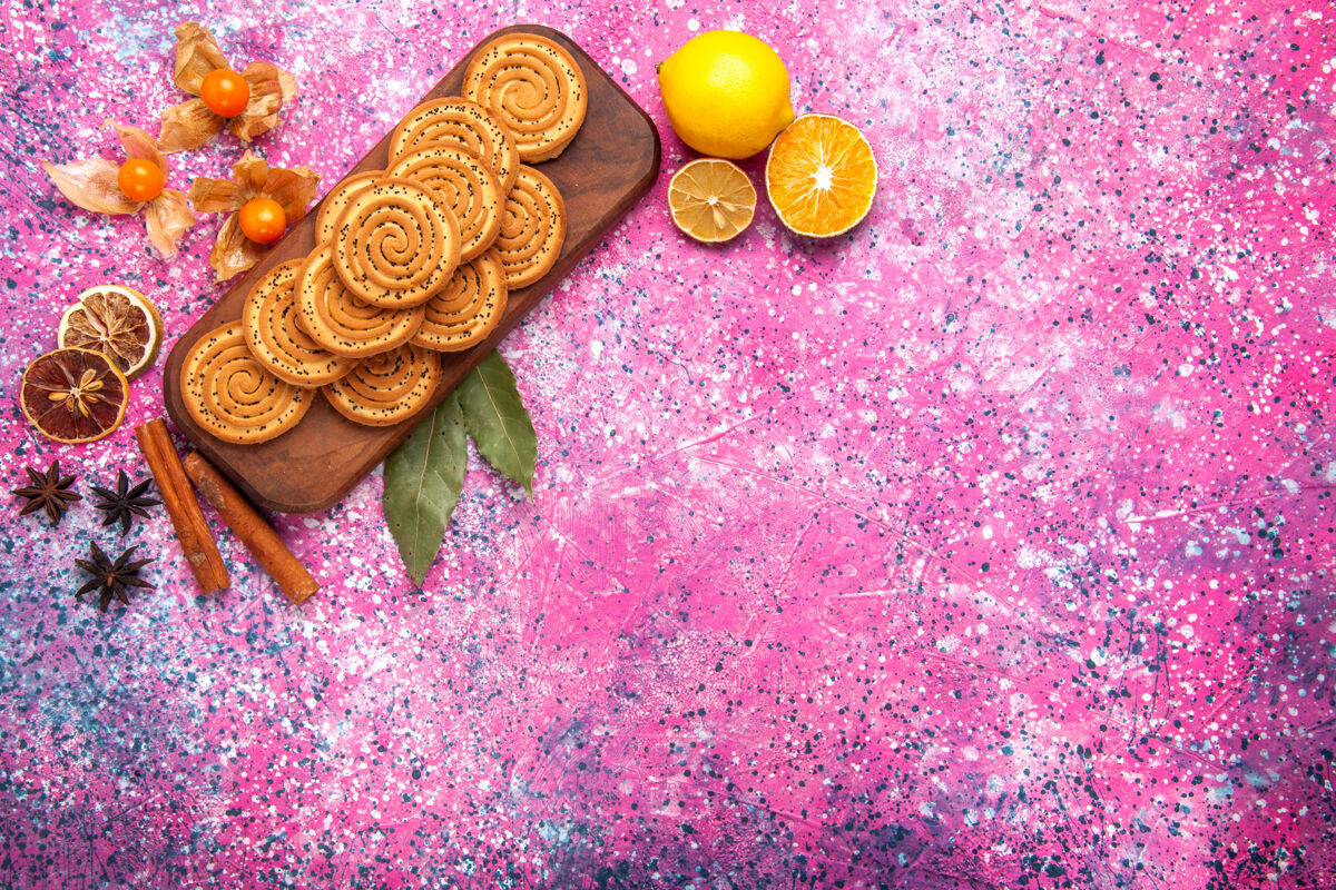 花粉红色表面上点缀着肉桂和柠檬的圆形甜饼俯视图柠檬内衬饼干