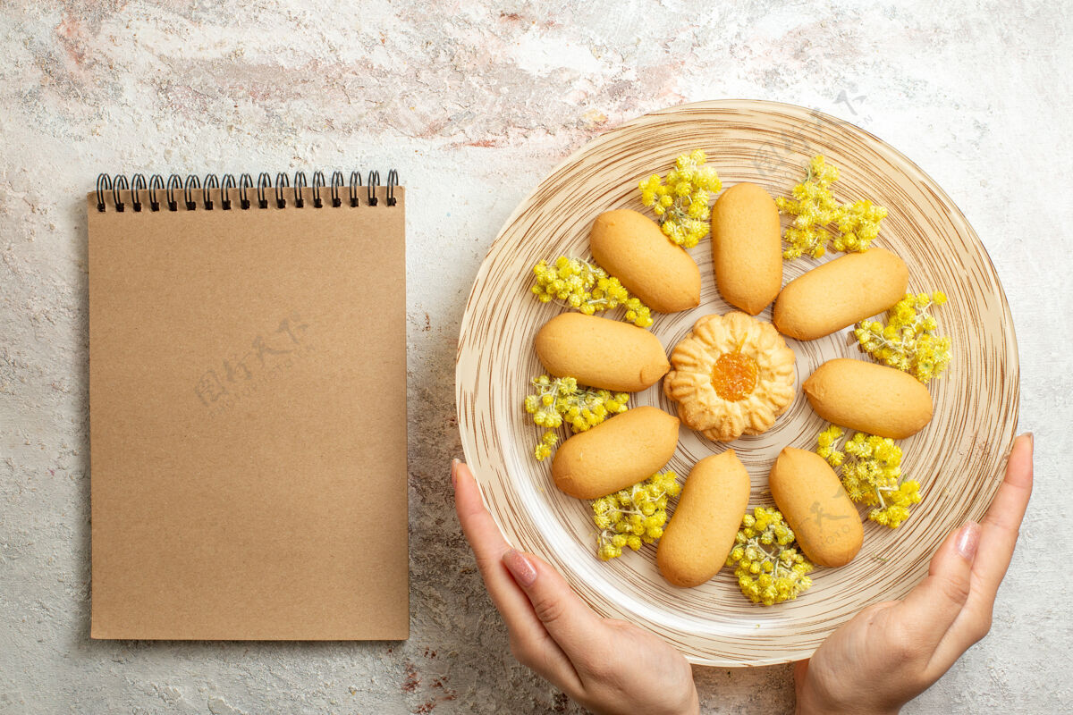 一餐一个女人拿着一盘美味的饼干放在笔记本旁边食物持有美味