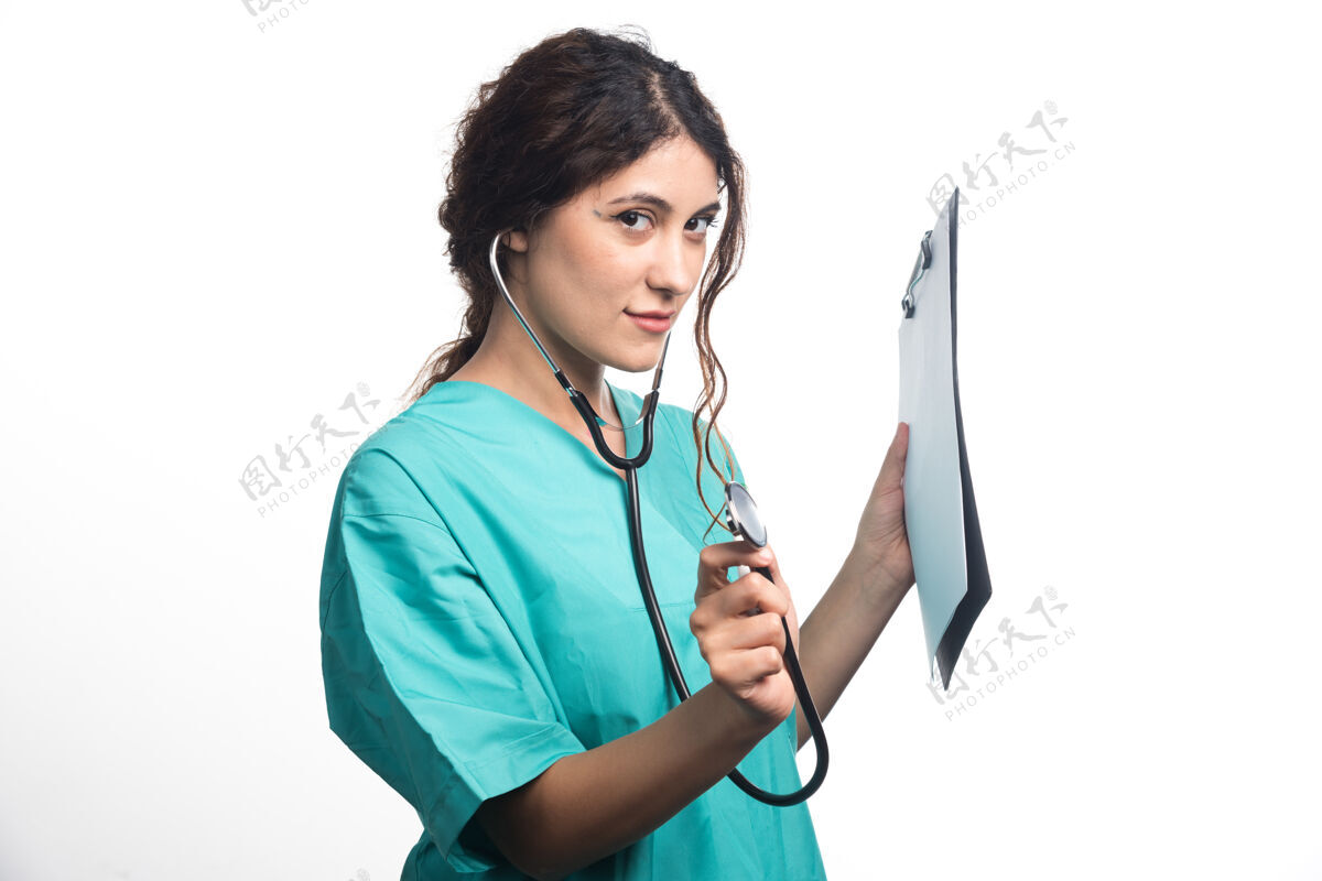 医生年轻的女医生 手持听诊器 穿着白色背景的制服拿着剪贴板高质量的照片医疗医生护士