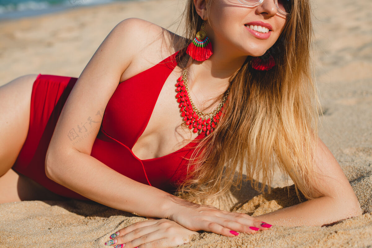 人年轻漂亮的金发女人穿着红色泳衣 戴着墨镜在沙滩上晒太阳漂亮性感头发