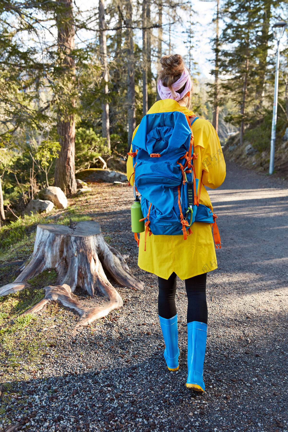 森林活跃的女探险家走在森林里的小路上 享受晴朗的天气 穿着黄色雨衣风景探索背包