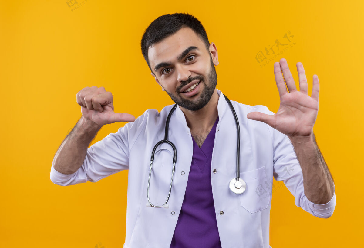 男性微笑的年轻男医生穿着听诊器医用长袍 在孤立的黄色背景上显示出不同的姿势穿着展示医学