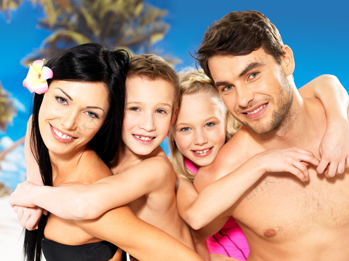 海岸在热带海滩 一个快乐微笑的美丽家庭和两个孩子的画像晒黑泳装热带