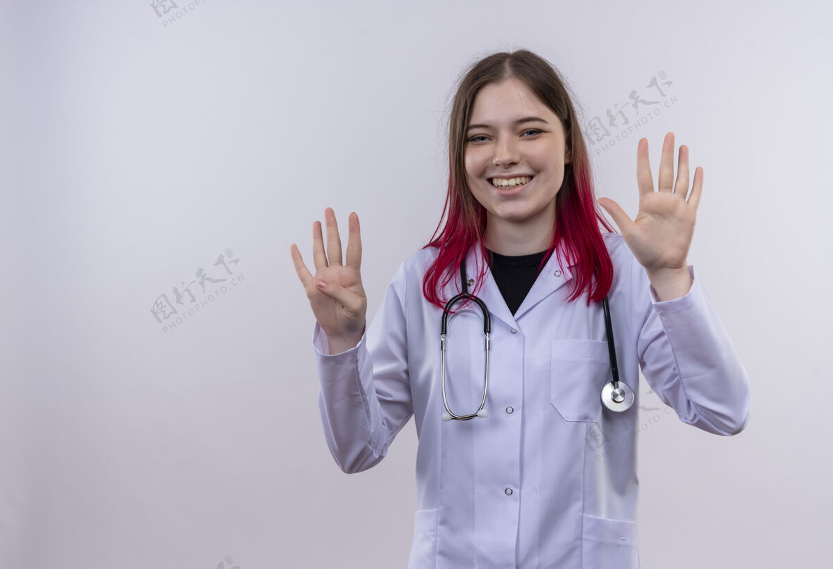 听诊器微笑的年轻女医生穿着听诊器医用长袍 在白色背景上显示不同的数字 并留有复印空间复制微笑长袍