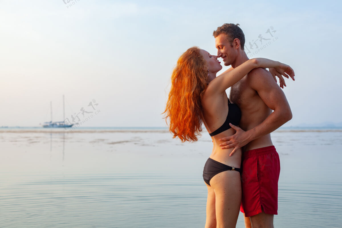 户外年轻性感浪漫的情侣在夏天的沙滩上快乐地穿着泳装玩海岸快乐年轻