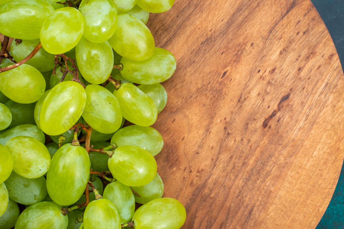 葡萄酒在深蓝色的桌子上近距离观赏新鲜的绿色葡萄 醇厚多汁的水果葡萄藤灌木顶部