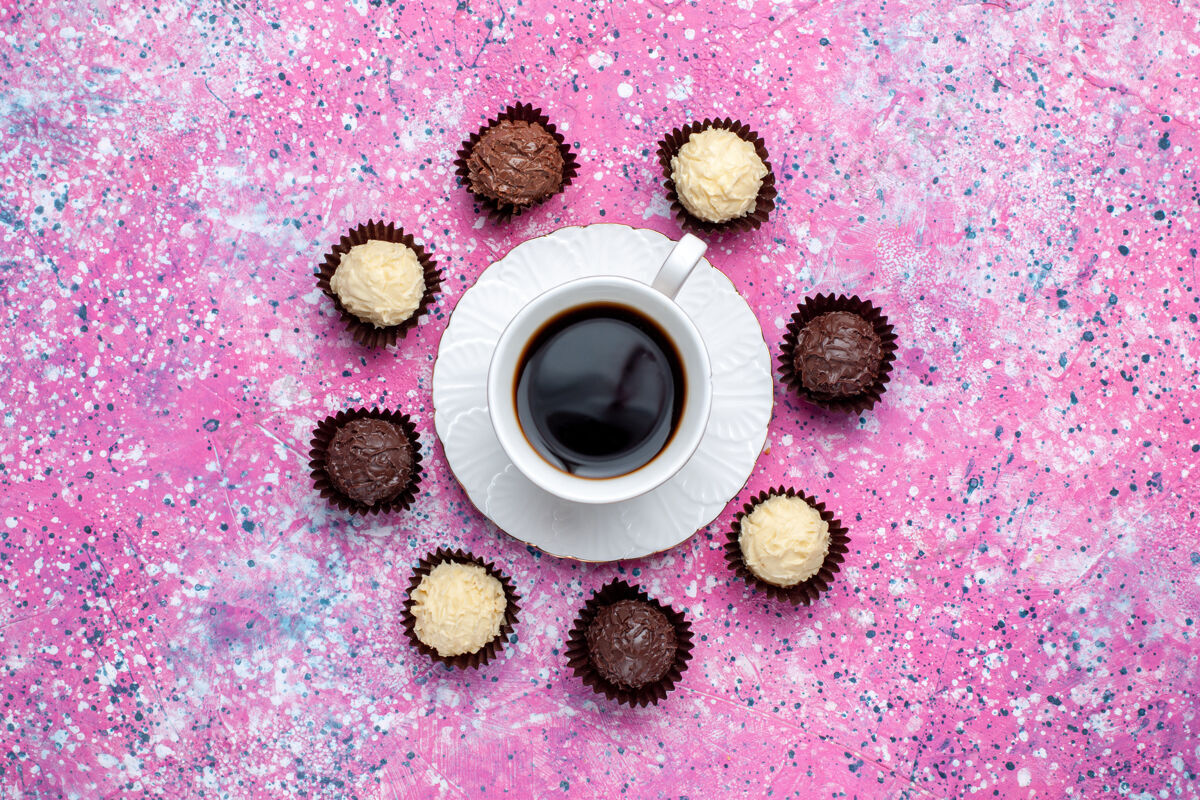 白俯瞰美味的巧克力糖果白色和黑巧克力 粉红色的桌子上放着一杯茶科技甜音乐