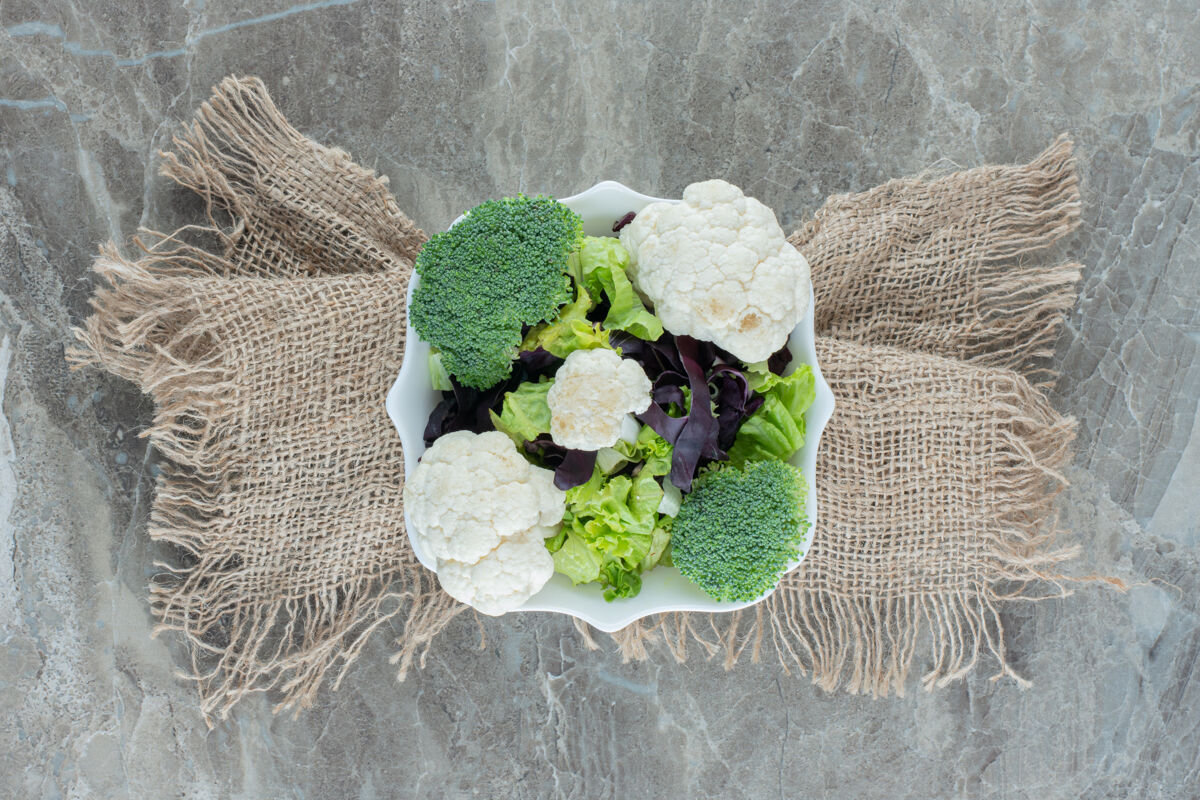 素食一盘花椰菜和花椰菜放在一块布包裹的大理石底座上花椰菜顶部视图饮食