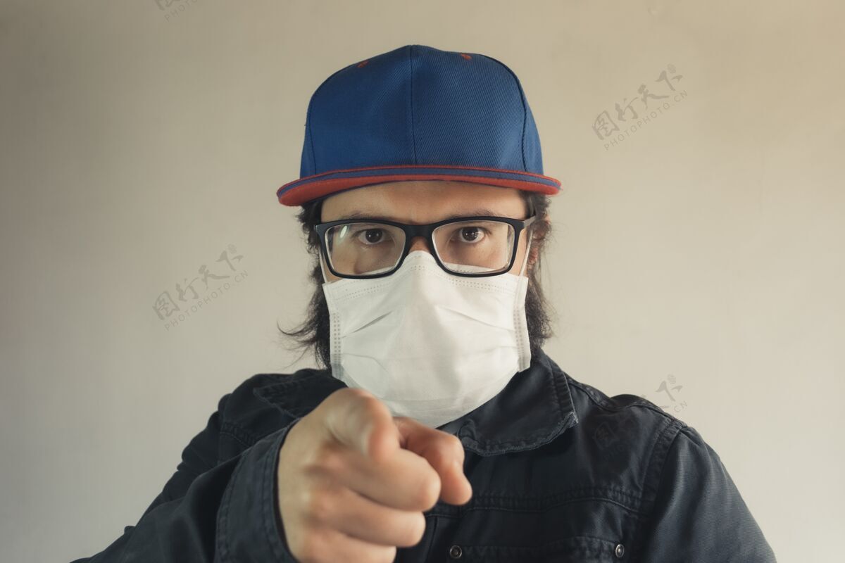 安全一个戴着蓝色帽子的人指着你戴着白色面罩以防灰尘和冠状病毒防护帽子指尖