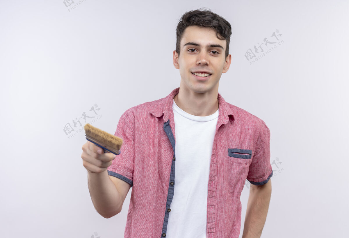 微笑微笑的白人年轻人穿着粉色衬衫 站在隔离的白色背景上对着相机画笔年轻衬衫抱着