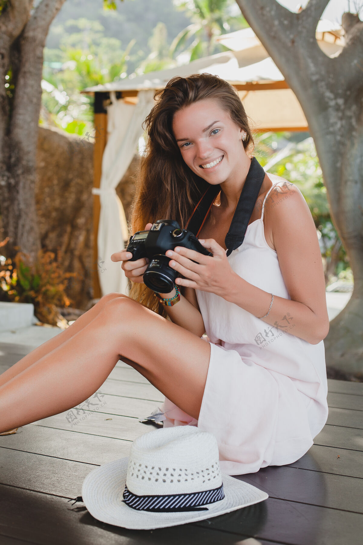 夏天年轻女子光着脚坐在地板上 穿着苍白的裙子 微笑着女人度假村肖像