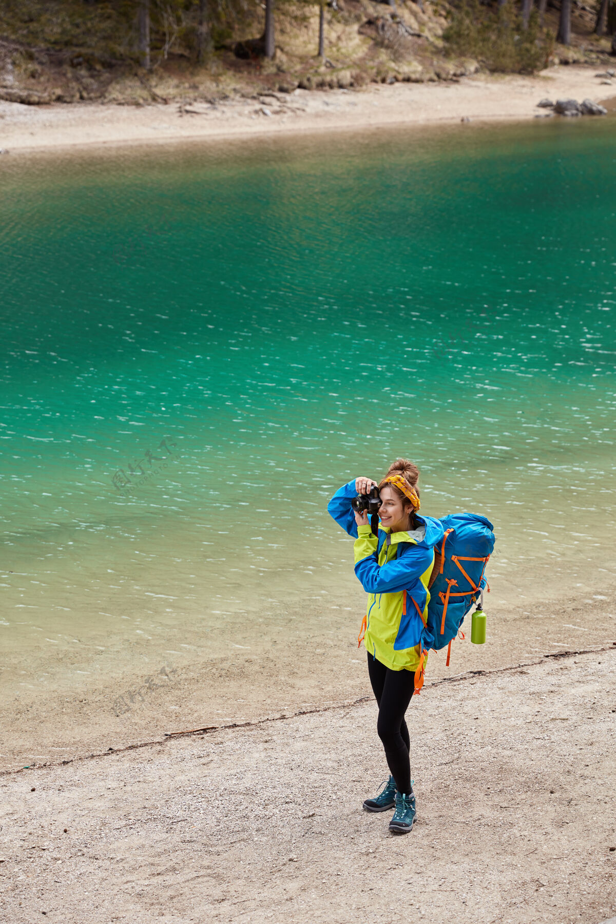 垂直活动女的俯视站在山青湖畔 在相机上拍摄东西 拎着大包探险休闲冒险