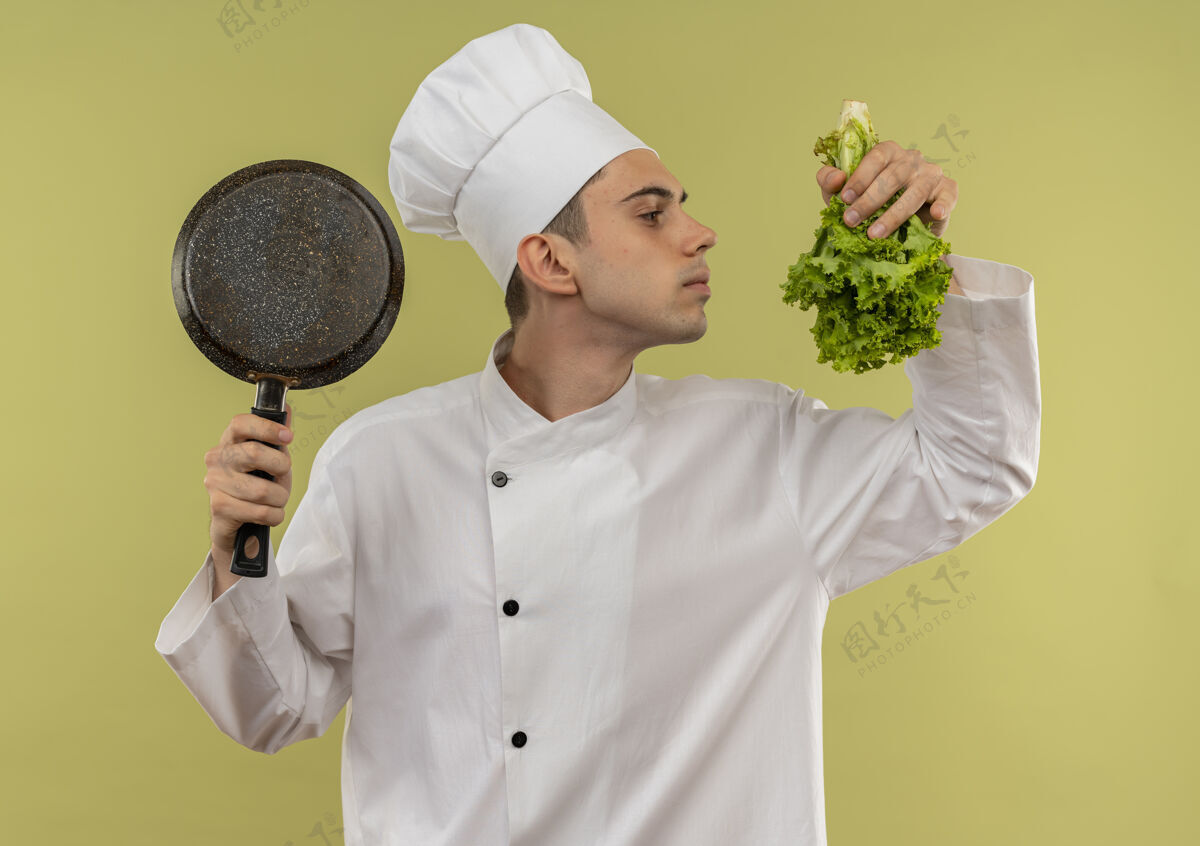 嗅站在剖面图上的年轻男厨师身穿厨师制服 手里拿着煎锅 嗅着沙拉厨师持有厨师