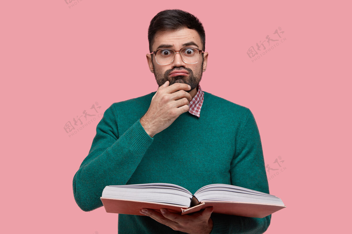 个人表情搞笑的惊讶男成人照片 托着下巴 留着深色的胡茬 端着打开的书惊喜眼镜教育