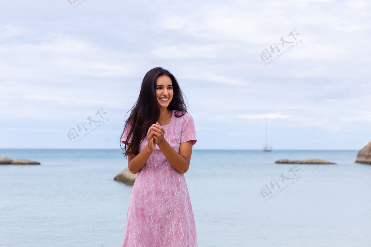 微笑一个年轻浪漫的女人 留着长长的黑发 穿着裙子 在沙滩上微笑着 笑着 一个人度过了一段美好的时光迷人肖像平静