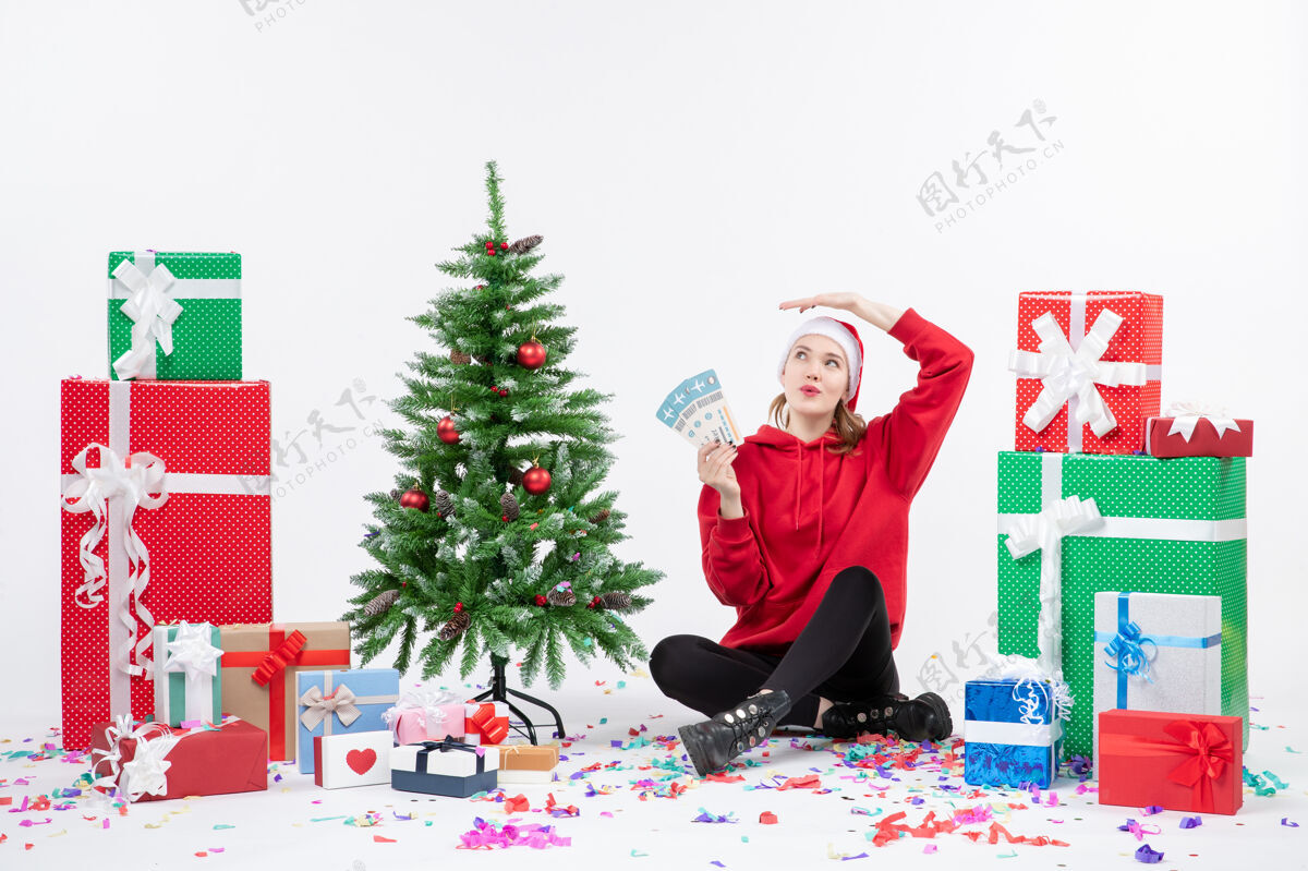 圣诞前视图年轻女子围坐在白墙上拿着飞机票的礼物礼物礼物抱着