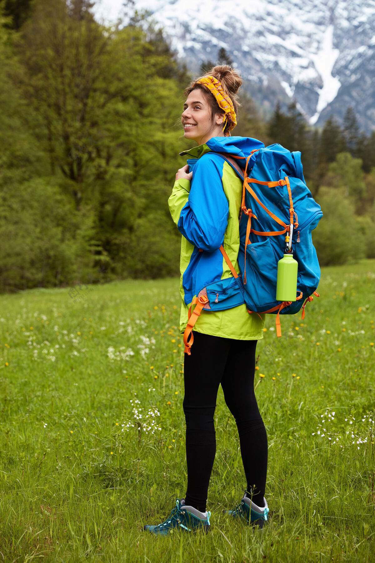 登山穿着运动服 漫步在绿色草地上的快乐的活动女游客的垂直全长镜头风景活跃背包