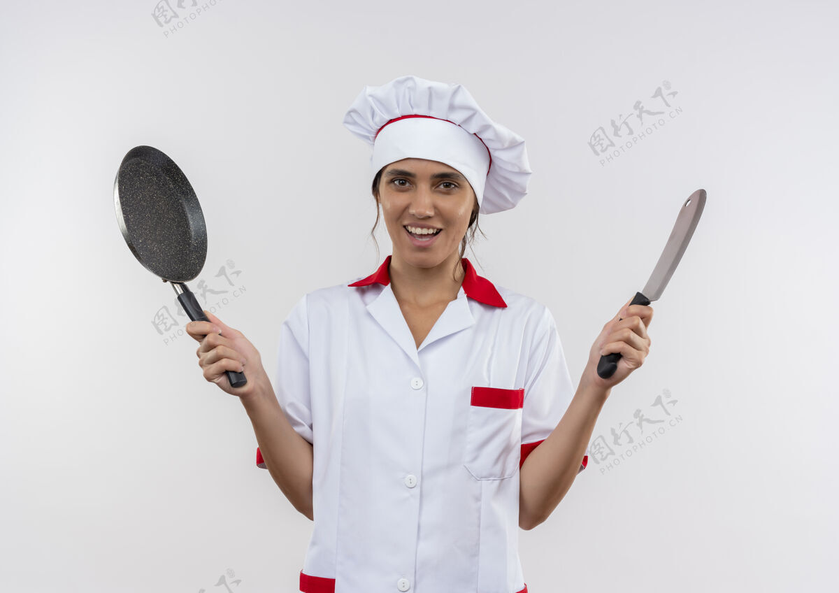 手持面带微笑的年轻女厨师穿着厨师制服拿着煎锅和切肉刀 还有复印空间煎炸切肉刀女