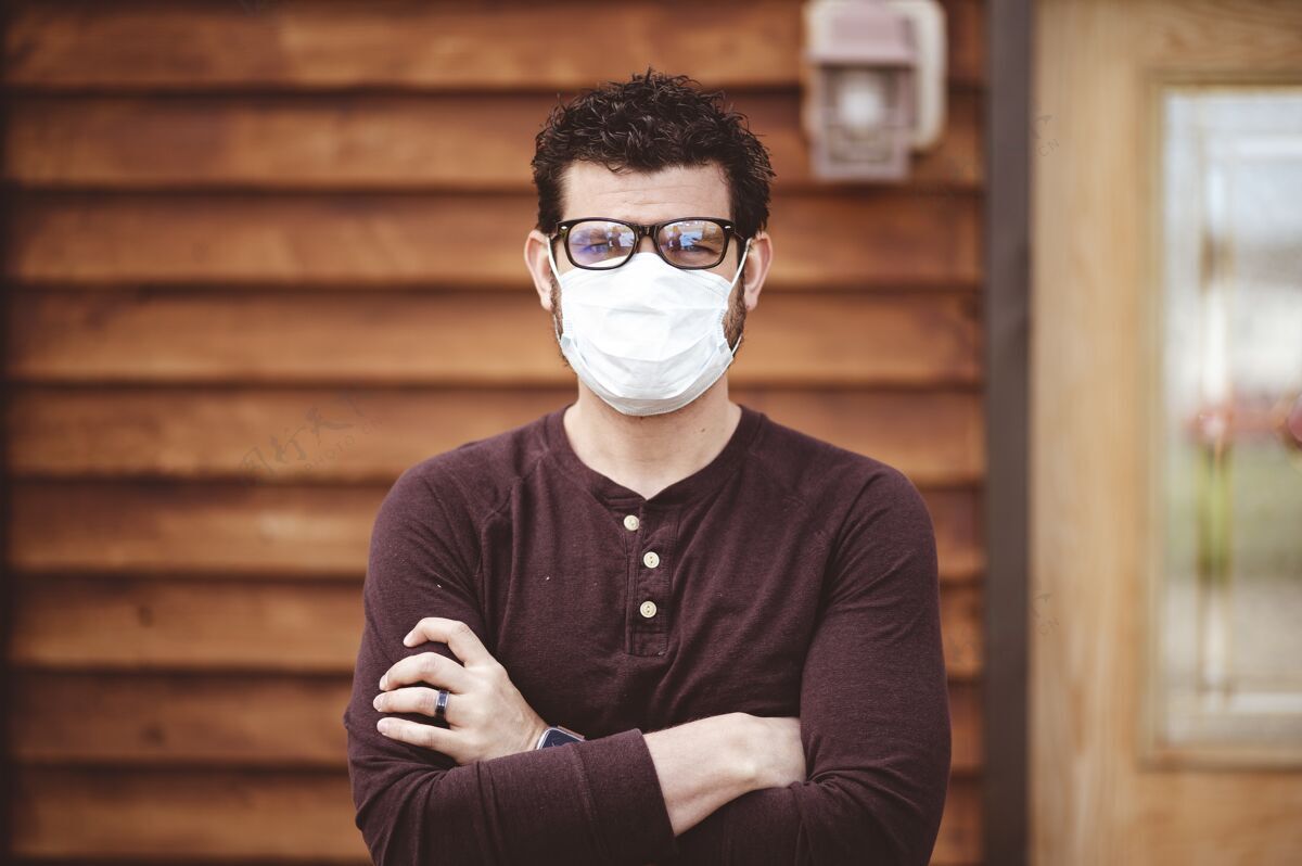 眼镜男人戴着眼镜和卫生口罩交叉双臂站在木墙前高加索面具防护