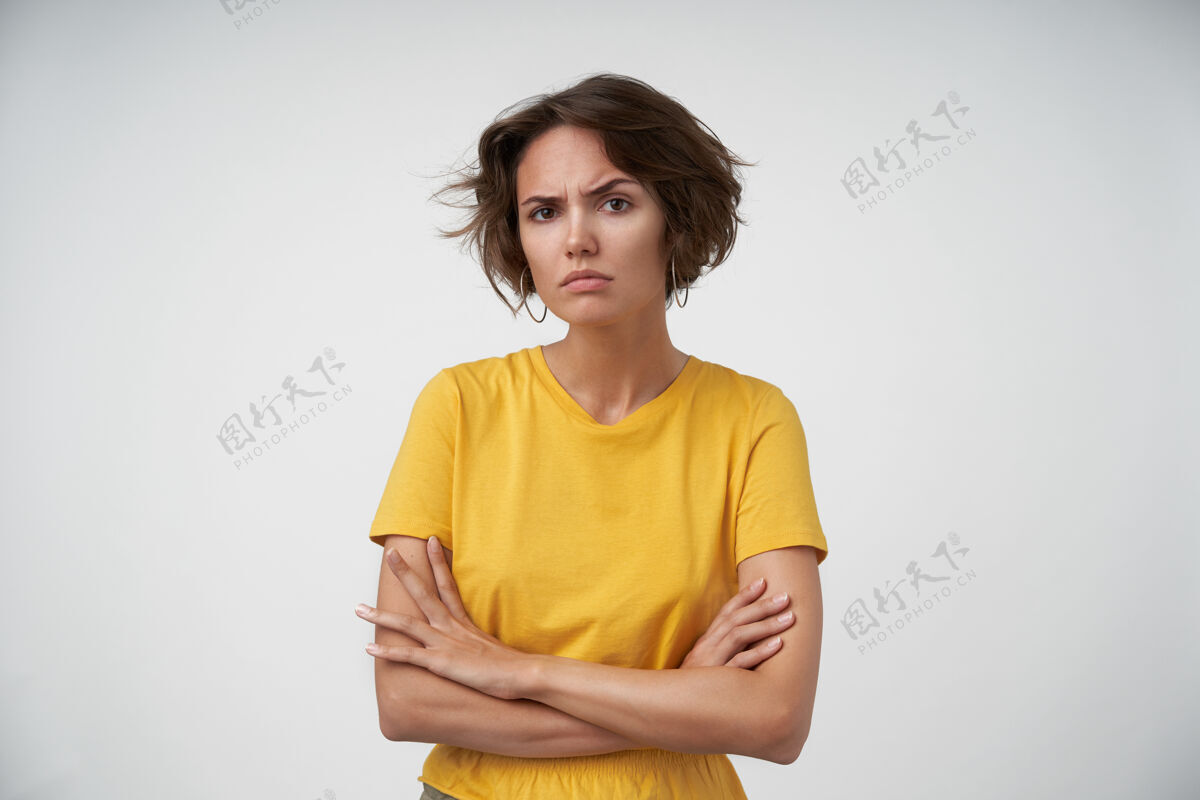 严重迷惑不解的漂亮女性 棕色短发皱眉 表情严肃 穿着黄色t恤 双手合十摆姿势休闲表情严肃
