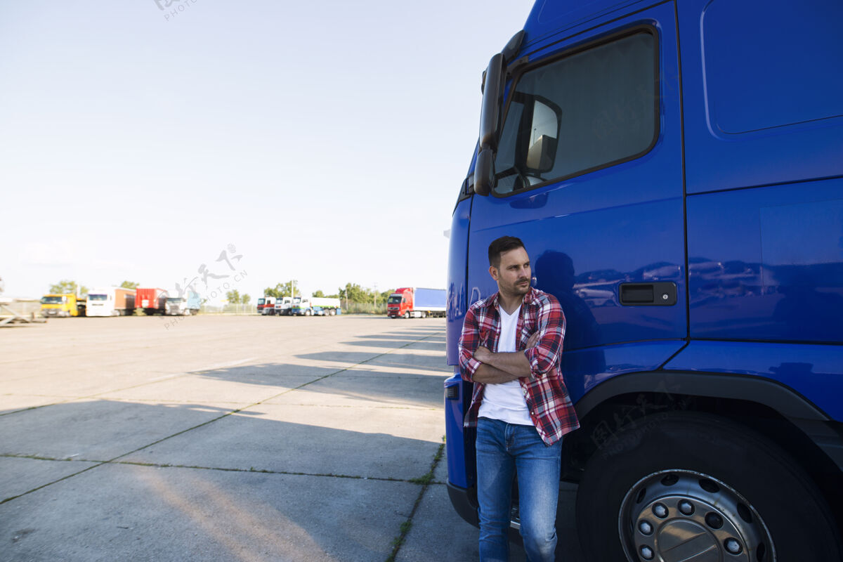 拖车一个穿着便服的卡车司机站在他的卡车旁侧视的画像驾驶车厢长