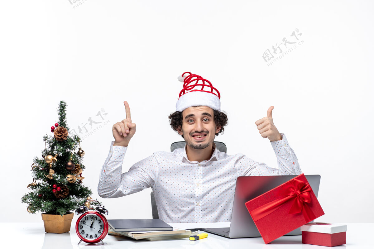 帽子快乐的年轻商人 戴着滑稽的圣诞老人帽子 在白色背景的办公室里做着“ok”的手势年轻的商人工作年轻的