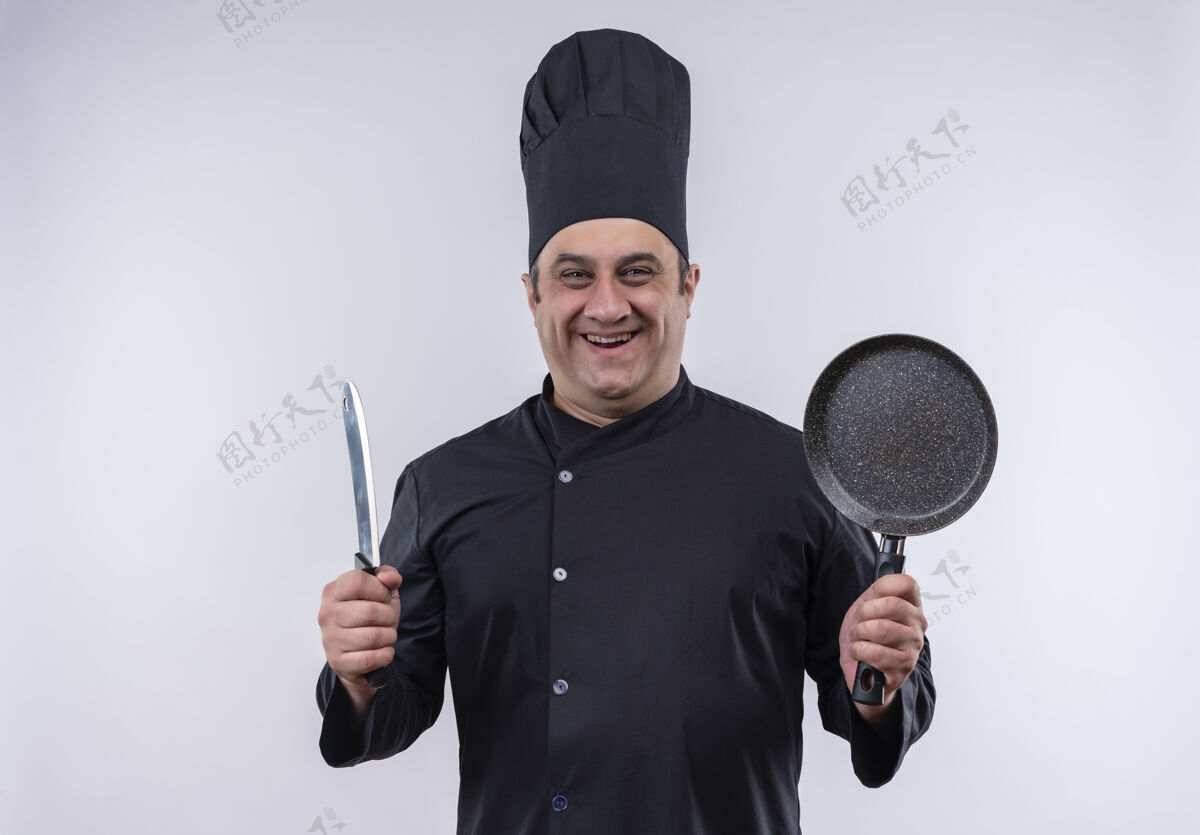 厨师微笑的中年男厨师 身着厨师制服 手里拿着煎锅和切肉刀 还有复印空间厨师中年平底锅
