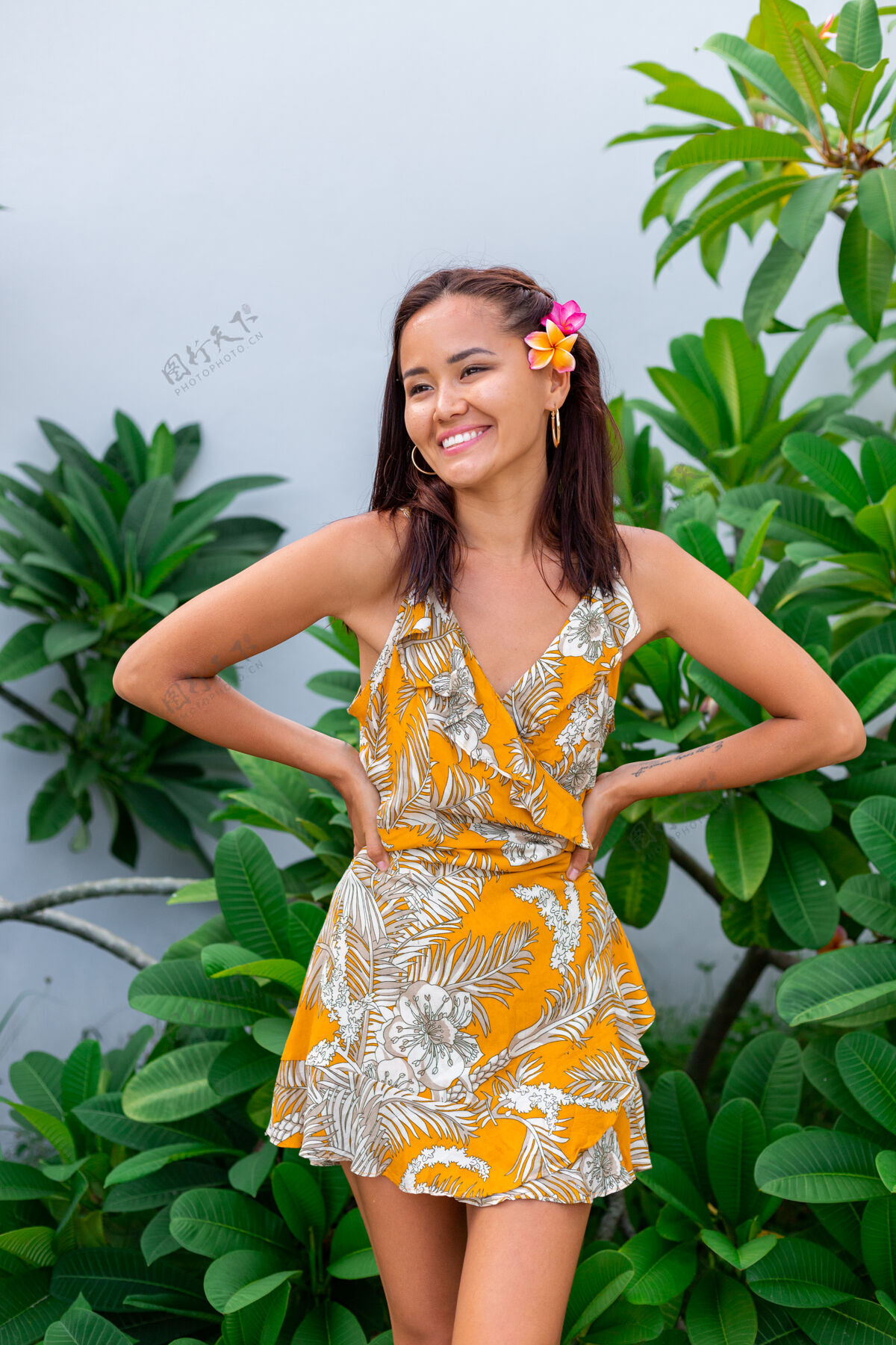 肖像身着黄色夏装的亚洲女人的肖像站在那里 头发上插着泰国花 戴着圆耳环年轻灌木泰国