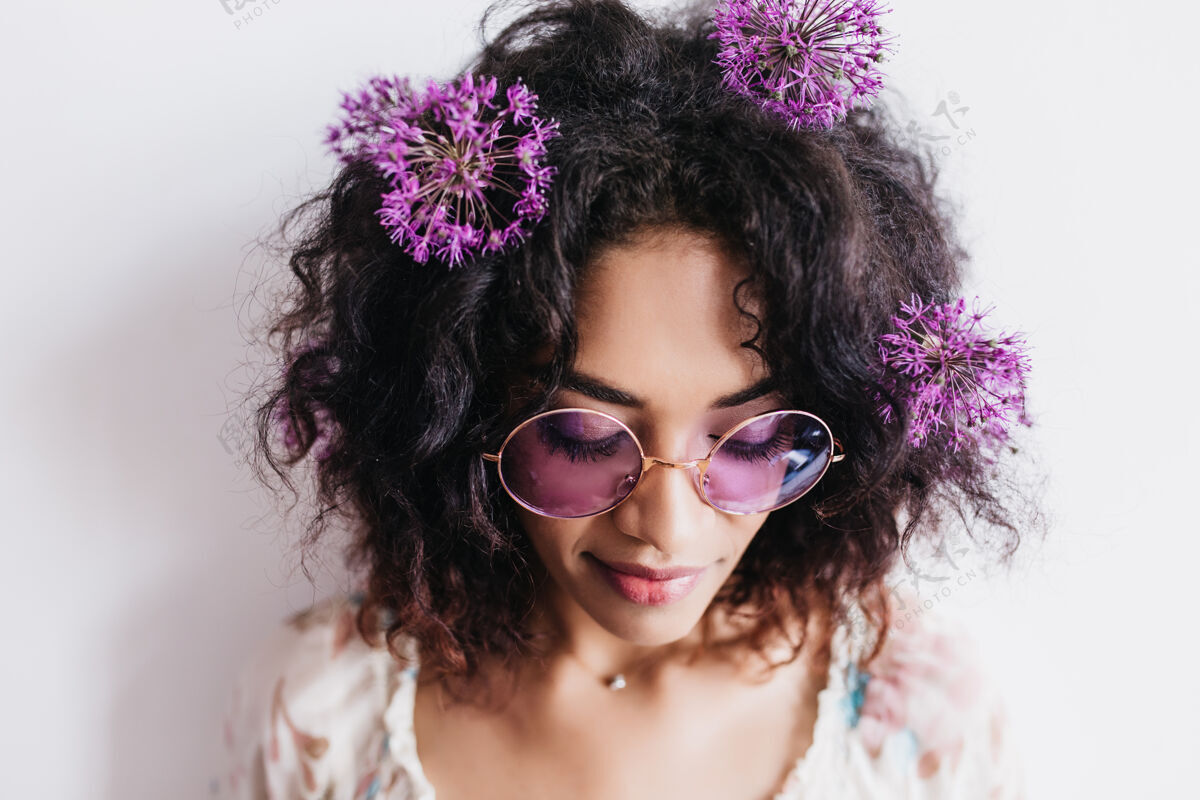 积极美丽的非洲女人戴着墨镜闭着眼睛的特写镜头美丽的女模特 深色头发 紫色的花朵休闲黑色成人