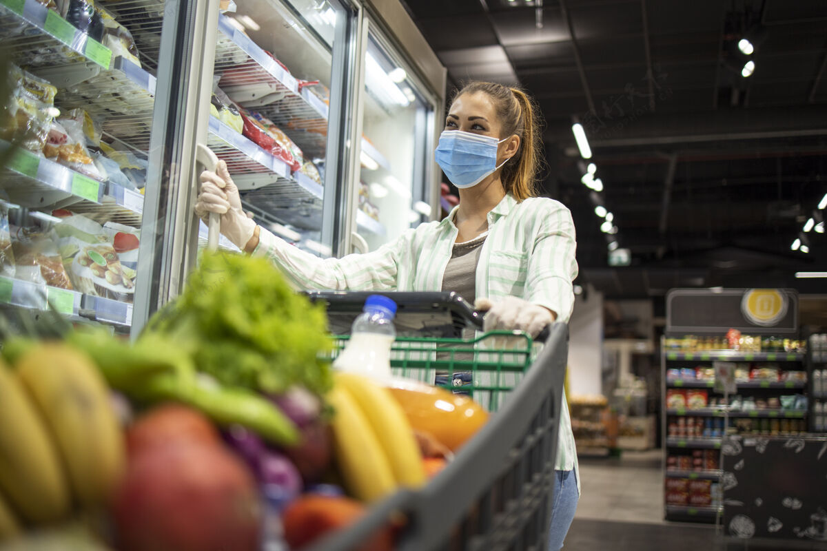 购物戴着防护面具和手套的妇女在超市购物时 在冠状病毒-19大流行或电晕病毒健康食品杂货店购物者