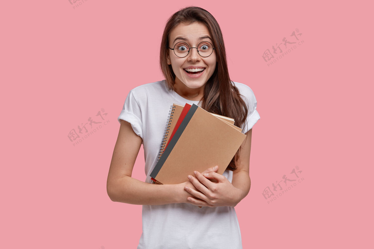 记事本快乐黑发女子的照片载着螺旋形记事本 笑容灿烂黑发青少年日记