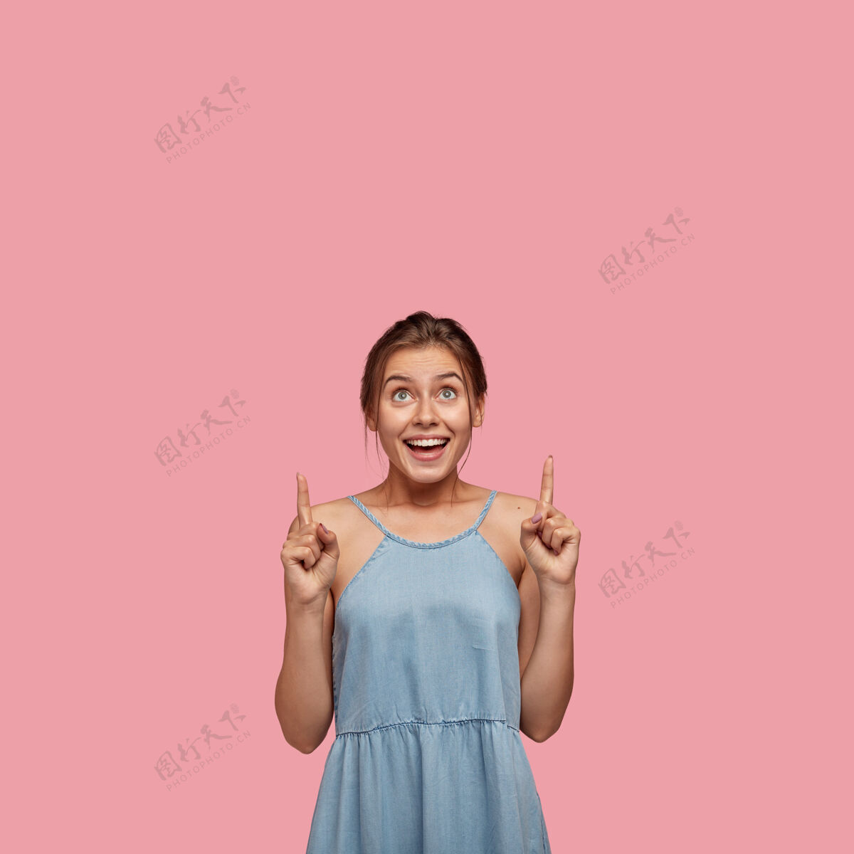 孤独快乐的年轻女性的垂直镜头 向上指 展示自由空间 穿着时尚的夏装指向微笑示范