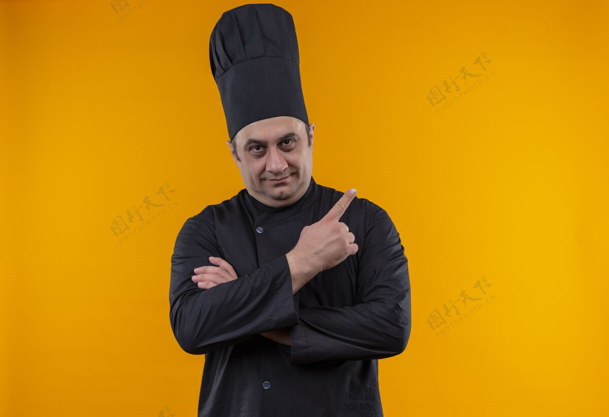 中年身着厨师制服的中年男厨师将手指指向黄色墙壁的侧面 并留有复印空间手指侧厨师