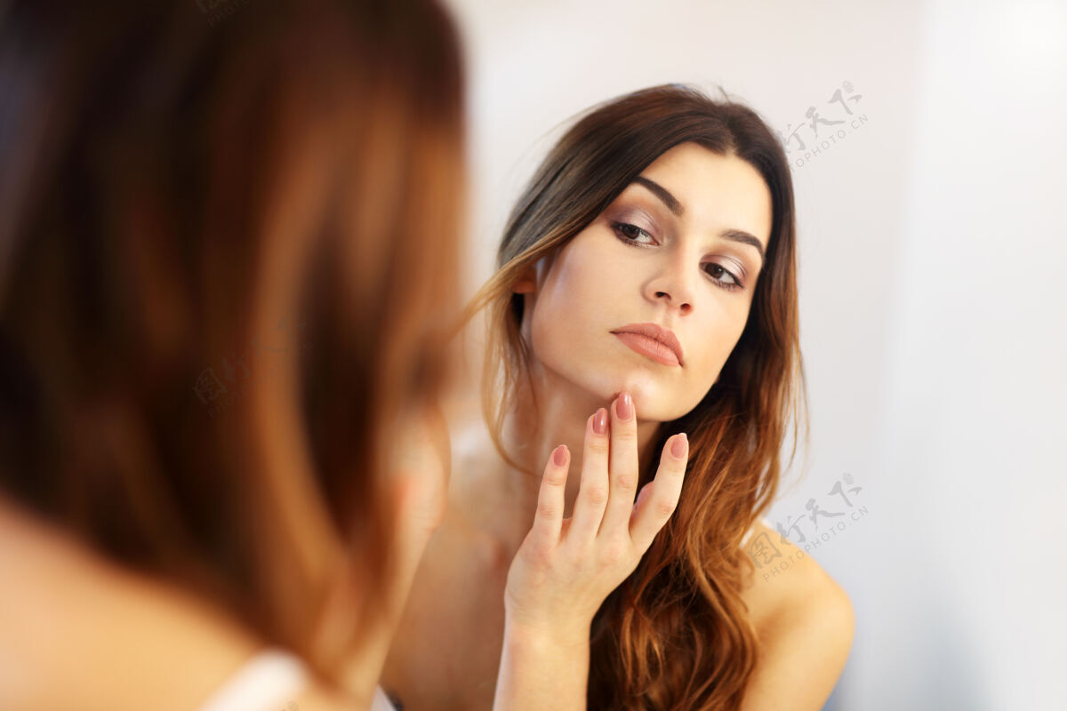 微笑在浴室镜子里看的年轻女人护理自然卸妆液
